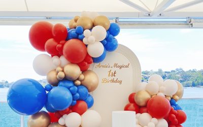 A Bold Red, Blue and Gold Balloon Backdrop Installation for a Waterfront Celebration
